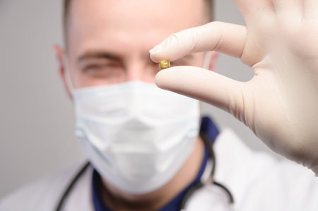 A young male doctor in a white coat and a protective mask holds a handful of omega-three pills on his hand. Invites them to acceptの写真素材