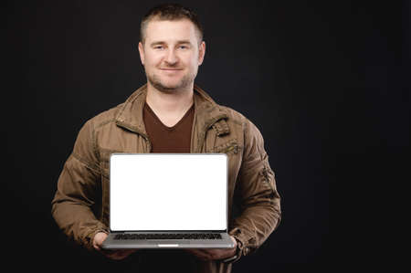 Portrait Caucasian attractive friendly man casual look is holding a laptop and looking at the camera. Cut out laptop screen presentation of projectの写真素材