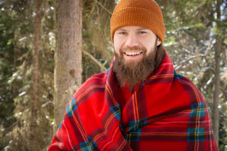 Portrait of happy young man with beard in snowy forest. Smiling man with beard in winter time. Winter mood. Sport man hiking in mountains.の写真素材