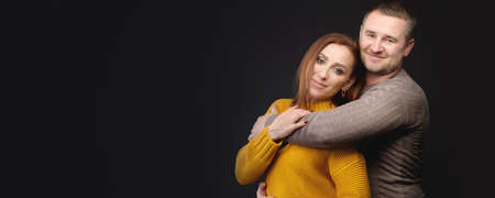 panoramic Looking at the camera Caucasian married couple man and woman hugging and kissing eyes closed. Casual style and bright clothes of an ordinary 30-year-old couple studio portraitの写真素材
