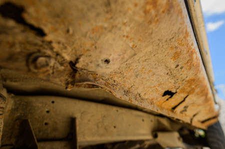 Body repair and welding work required. Rust on a gray old car. Rust hole on an old worn out painted...