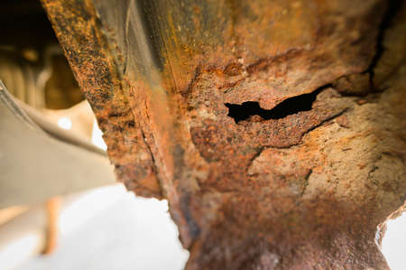 Close-up Body repair and welding work required. Rust on a gray old car. Rust hole on an old worn out...
