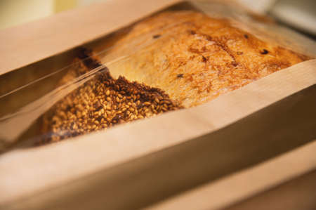 a loaf of white artisan hot bread in a paper bag with transparent inserts on a white background. Healthy food. Homemade natural productsの写真素材