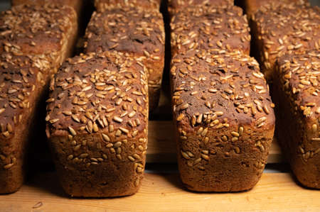 Close-up fresh brown loaves of rye bread in the form of bricks with sunflower seeds on a crust. Lie...