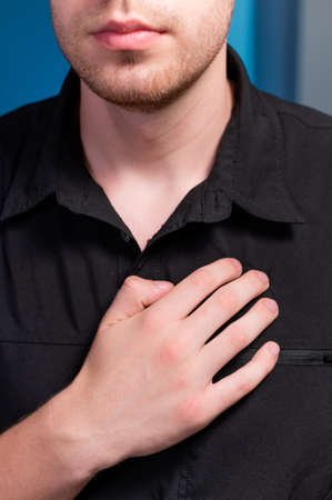 Close-up of a man in dark clothes, a masseur doing self-massage of the chest and pectoral musclesの写真素材