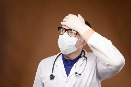 Young caucasian doctor in a medical uniform makes a facepalm gesture. Medical errors and stupidityの写真素材