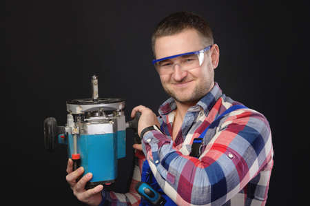 Friendly smile caucasian male carpenter with a wood cutter in his hands. Portrait of a man working with a tree on a black backgroundの写真素材