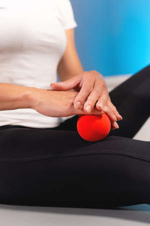 Close-up of a male massage therapist showing a client how to use and massage a ball. Myofascial thigh massageの写真素材