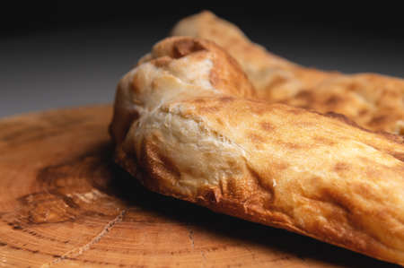 Close-up fried khachapuri cooked in the oven lies on a wooden boardの写真素材