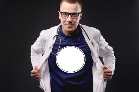 Doctor superhero. Young caucasian man in medical overalls, copy space on his chest. Isolated white circle on the chest for your logoの写真素材