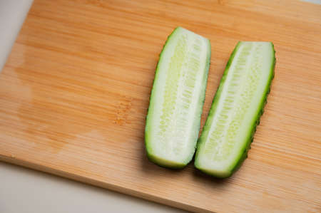 juicy ripe cucumber cut in half lies on a wooden cutting board, top viewの写真素材