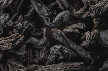 Extreme macro Black loose leaf tea as a background. Texture of dry black tea leaves in shallow depth of field. Dark background. macro mode. black leaf tea closeupの写真素材