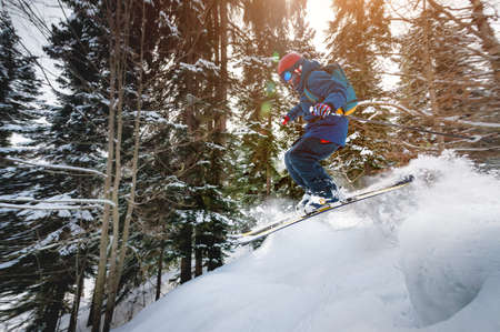 A male athlete skier rides a freeride in a winter forest in the mountains. Jump against the backdrop...