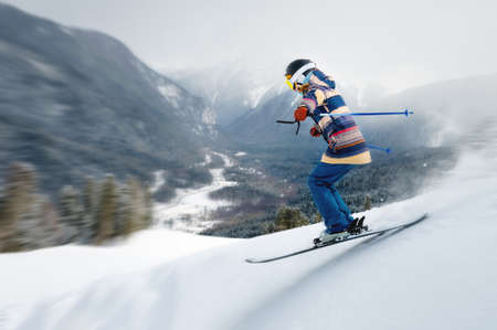 A female athlete skier rides a freeride in a winter forest in the mountains. Jump against the backdrop of snow-covered trees and the setting sunの写真素材