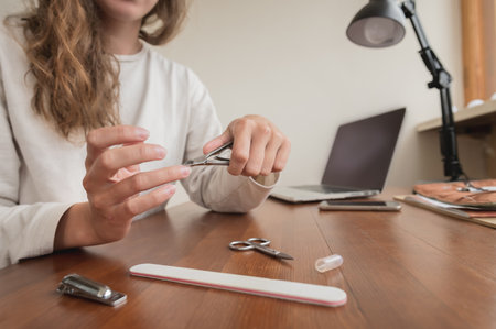 Close-up of hand of caucasian young woman doing manicure at home with nail supplies.の写真素材