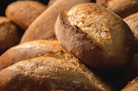 Fresh crispy hot delicious craft artisan bread. Many loaves lie on a wooden pallet