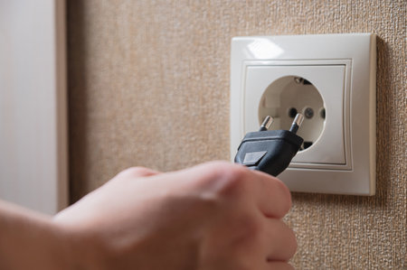 A young woman inserts a plug into a socket. A young woman plugs a charger or electrical appliance power cord into a socket. High quality photoの写真素材
