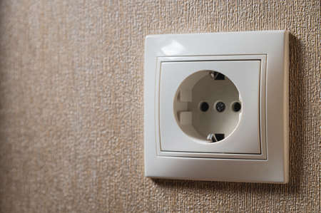 Wall socket, white electric socket on wallpaper background