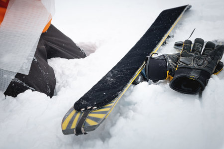 The skier stopped to put skins on skis. Gloves lie on the snow next to the ski. Trekking equipment...