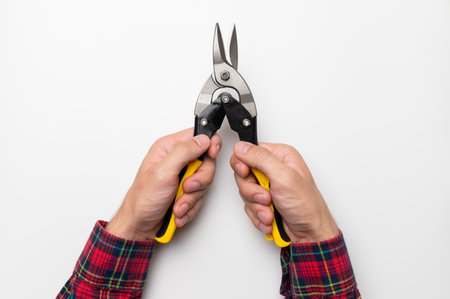male hands hold yellow bright tongs of a construction tool, on a white background. pliers closeupの写真素材