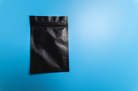 black small bag with a zipper lies on a blue background, there is a place for the inscription