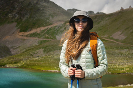 Portrait of a smiling woman resting during a mountain hike. A woman with a backpack enjoys the view,...