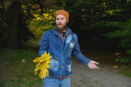 Portrait of a happy positive man with a wide smile in casual clothes on an autumn walk in the parkの写真素材