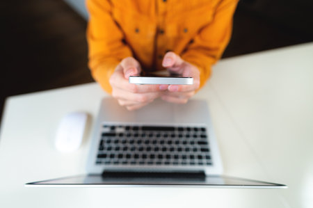 Business woman using mobile smart phone and working on laptop computer with digital tablet on office...