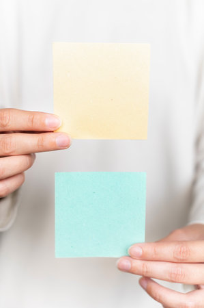 Hands holding empty booklets of brochures, on a blurred white background of a jacket. Sheet...
