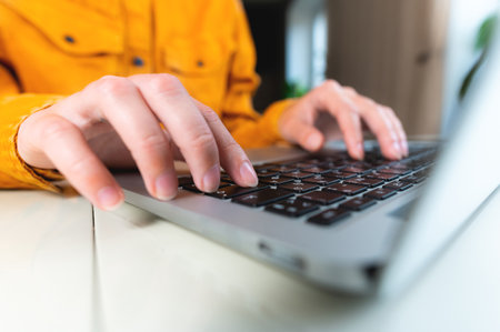 Close up image of woman hands typing on laptop computer keyboard and surfing the internet on office...