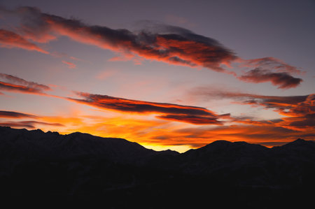 Mountains in the clouds at sunset in summer. Aerial view of the mountain peaks in the fog. Beautiful...