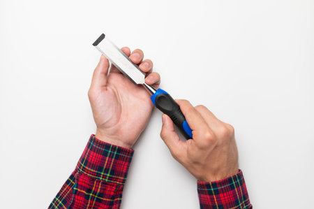 Hand tool chisel on a white background in a mans hand, top view. Craftsman in a plaid shirt holds a...