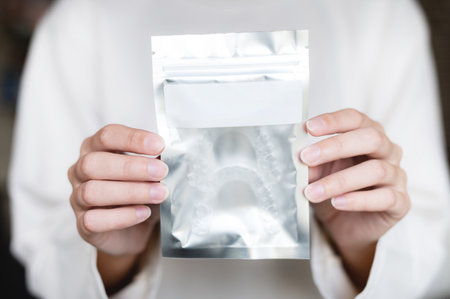 womans hand holds a paper bag with a zip lock and an empty tag for a note, inside there are new transparent braces, close-upの写真素材