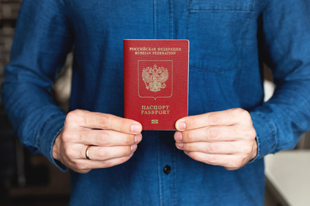 Russian foreign passport in the hands of a man in a blue denim shirtの写真素材