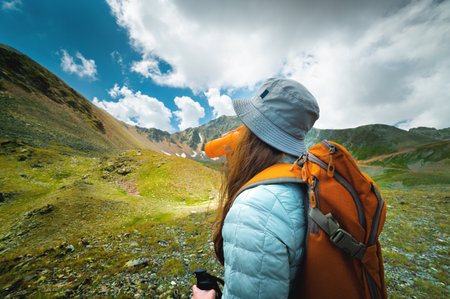 successful tourist drinks water in a green meadow near high mountains. Travel and hiking concept...