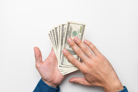 human hand with money on a white background. male hands in a shirt hold out and spend one hundred dollar billsの写真素材