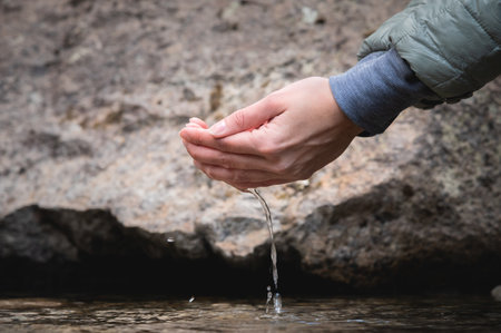 Mountain spring. A woman washes her hands in fresh, natural, cold drinking water. Ecology of the planet. Close-upの写真素材