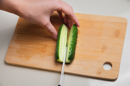 green cucumbers are cut with a knife in the kitchen. healthy food salad vegetables concept. close-up green cucumbers in the kitchen hands close-up cut into slices lifestyleの写真素材