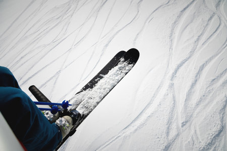 A skier sits on a chair lift on a beautiful day, Alpine mountains. Skiing concept. Side view of a skier on the ski liftの写真素材