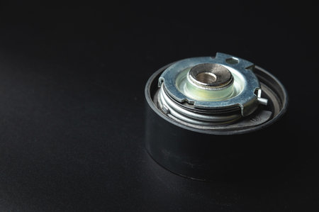 Close-up of a timing belt tensioner on a black background