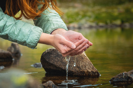 palms touch the water in the pond. Water in womans hands. Woman takes clean water in her hands from the lakeの写真素材