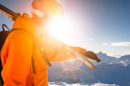 young skier in ski goggles in the mountains and bright clothes stands against the background of a clear sky and a sunny day. horizontal viewの写真素材