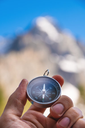 man holds a compass in his hand against the backdrop of mountains, blurred background, close-up....