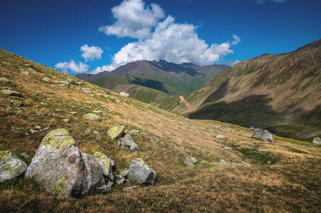 Rocky slopes of autumn mountains with clouds on the blue sky in the background. Journey in the mid-altitude mountainsの写真素材