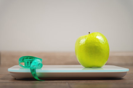 concept of weight loss, diet, healthy food, floor scales, measuring tape and an apple. Side view