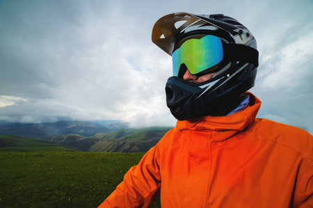 Portrait of a cyclist in a full-face helmet and sunglasses on the background of a mountain. Sport, motocross and portrait of a man in a helmet for off-road racing, mountain biking and trainingの写真素材