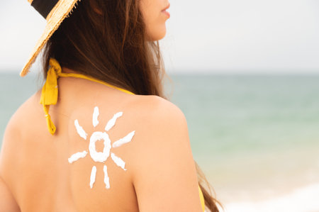 happy girl with the sun on her back by the sea in nature. drawing with cream in the shape of a sun on the back, skin care. Sun protection. Suntan creamの写真素材