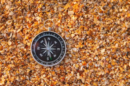 compass on sea sand and place for text. close up of navigation device on sandy beach without people, top viewの写真素材