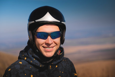 Portrait of a smiling young man with a parachute in a field. A guy paraglider in sportswear and a helmet is preparing for a flight or after landing outdoorsの写真素材