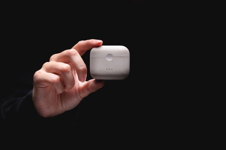 White wireless headphones. in the womans hand there is a charger box for vacuum headphones, a white...